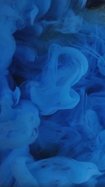 Dikey video. Mürekkep patlaması. Duman bulutu. Soyut mor parıldayan sanat arka planında odaklanmış mavi renk sisi dokusunun buharı, ışıl ışıl parlıyor..