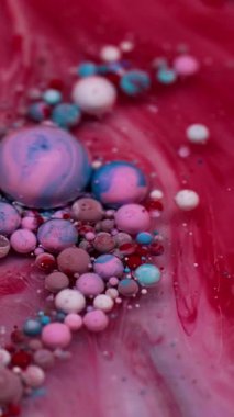 Dikey video. Boya karışımı. Yağ kabarcıkları. Renkli akrilik damlaları karıştıran parlak mermer bulanıklığı. Dalga suyu kırmızı pembe mavi sızıntı soyut arkaplan.