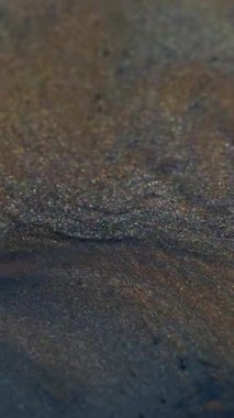 Dikey video. Parlayan koyu sıvı. Sihirli damla. Fantezi sıvısı akışı parlayan volkanik siyah gri küller boya dalgası soyut bulanık arkaplan.