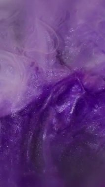 Dikey video. Renk dumanı. Boya patlıyor. Beyaz mat mor parıldayan mürekkep dumanı koyu suya karışıyor. Soyut arkaplan parçacıkları kırık cam ampul.