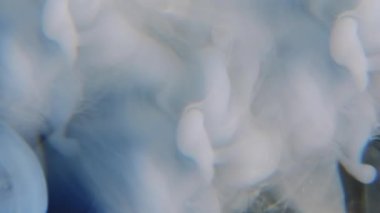 Su köpüğü. Mürekkep at. Su karışımında çözünmüş mavi renkli bulut dokusu soyut sanatın koyu siyah arka planında sallanıyor..