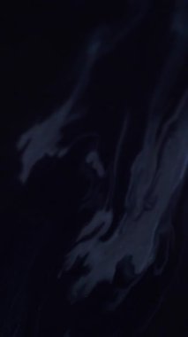 Dikey video. Sanat sıvısı. Grunge akışı. Kirli, kirli gri lekeler. Boya, gizemli, siyah yüzeyi soyut olarak kurutur. Koyu pigment karışımı eriyen sıvı.