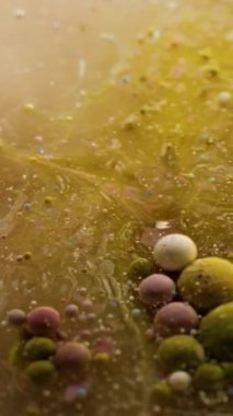 Dikey video. Mermer sıvısı. Emülsiyonu bırak. Sarı kahverengi yağ sıvısı dokusunu çözme fantezisi. Odaklanmamış boya akışı soyut arkaplan.