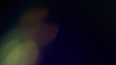 Ray parıldıyor. Bulanık soyut ışık. Odaklanmamış sarı gökkuşağı spektrumu aydınlatma deseni koyu siyah arka planda parıldıyor..