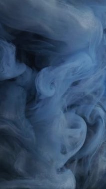 Dikey video. Duman peçesi. Mistik sis. Parlayan bulutla mavi gri mürekkep karışımı. Kozmik gaz desenli havadar parıltı tozu akışı su soyut arkaplan.