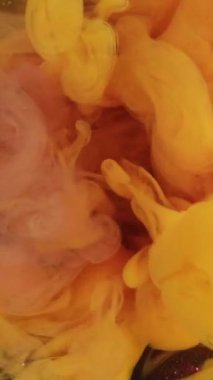 Dikey video. Renk dumanı. Boya sisi. Zarif turuncu, parlak metal arkaplanda hava akışı sağlar. Mistik sarı su girdap etkisi.