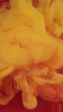 Dikey video. Boya sıvısı. Mürekkep suyu. Odaklanmamış sarı turuncu renkli sis dokusu dumanı soyut sanat arka planında daire şeklinde parlıyor..