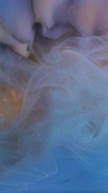 Dikey video. Lüks duman. Kozmik boya uçuyor. Odaklanmamış mavi renkli bulut desenli soyut altın sanat arkaplanına mürekkep dokusu sıçratır.