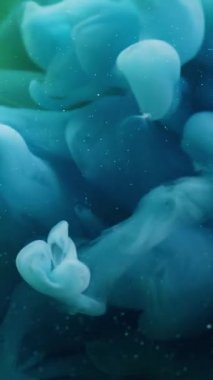 Dikey video. Fantezi dumanı. Boya dumanı. Suluboya mavi girdap yeşil suda yüzer. Gizemli mürekkep arkaplanı ve çözünmüş bulanık dokusu.