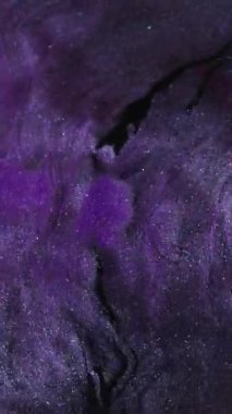 Dikey video. Parıltı akışı. Boya dökülmüş. Mor, düz olmayan, parlak, ıslak bir yüzey. Dalgalı koyu soyut arkaplana menekşe mürekkebi yayılıyor.