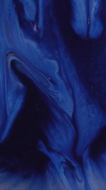 Dikey video. Mürekkep akışı. Sanat sıvısı. Beyaz ışıldayan toz donunun üzerine mavi sıvı dökülmüş. Renk parçacıklarını soyut bulanık arkaplanla karıştır.