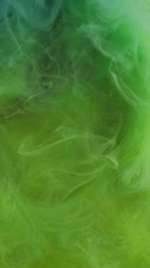 Dikey video. Sis dalgası. Renkli sis. Fırtınalı su akışında kabarık bulutlu sarı yeşil karışım mürekkep. Gizemli pürüzsüz dokuma arkaplanı olan havadar kıvırcık boya..