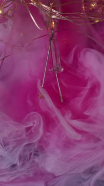 Dikey video. Suluboya patladı. Pembe duman. Dumanlı mürekkep yatıştırıcı. Karanlık su arkaplanında dalgalar yayıyor. Keskin cam ampuller de var..