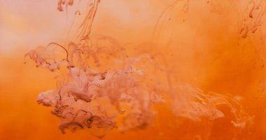 Pigment damlası suyu. Buhar akışı. Kahverengi boya parlak turuncu sıvıyla damlıyor. Sıcak renk dumanı karışımı çözünmüş soyut arkaplan.