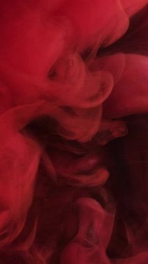 Dikey video. Kırmızı duman. Mistik sis. Havadan renkli dalgalı girdaplar döküldü. Fantezi bulutlu kabaran dalgalı boya suyun soyut arka planında akıyor..