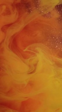 Dikey video. Sis sıvısı. Renkli suluboya. Pembe, parlak, soyut arka planda turuncu boya kıvrımları. Suda yarı saydam bulanık peçe boyası.