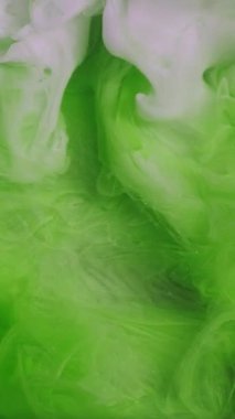 Dikey video. Renkli sis. Duman sıçrıyor. Odaklanmamış yeşil beyaz sıvı akışı sıvı bulut buharı boya boya mürekkep dokusu sanat desenli açık arkaplan.