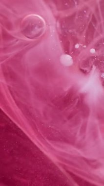 Dikey video. Duman sıvısı. Duman girdabı. Pembe boya pigmentlerini karıştıran bulanık boya. Parıldayan toz parçacıkları desen buhar soyut arkaplan yayıyor.