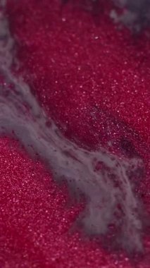 Dikey video. Sanatsal mürekkep. Sıçrama kanaması. Işıldayan pembe kum sıvı yüzeyine damlatın. Dalga akışı bulanık ıslak mermer soyut arkaplan.