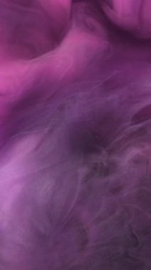 Dikey video. Mermer bulut. Mor duman. Mor boya sıvısı ve parlak parçacıklar garip bir şekilde spiraller. Odaklanmamış su soyut arkaplanındaki dalgalı peçe suluboya.