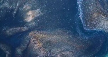 Parlak mürekkep. Akış dokusu. Odaklanmamış mavi altın rengi parlak sıvı serpintiler soyut yaratıcı akrilik arka plana yayılıyor.