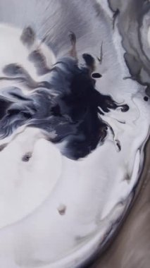 Dikey video. Grunge akışı. Siyah mürekkep. Koyu pigmentlerin kıvrımlı beyaz yüzey dokusu. Suyun soyut arka planında dumanlı mistik bukleler karışır.