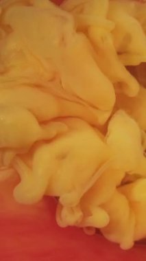 Dikey video. Mürekkep suyu patlaması. Duman çemberi çerçevesi. Odaklanmamış sarı sis dumanı soyut sanat arka planında ışıltılı boya dokusu.