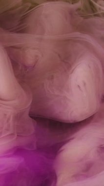 Dikey video. Renkli duman bulutu. Dalga sisi. Odaklanmamış pembe sisli boya mürekkep buharı soyut sarı parıldayan sanat arka planında parıldıyor..