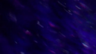 Parlak ışık. Odaklanamayan gökkuşağı yansıması. Mavi renk optik lensler bulanık koyu siyah soyut arka planda hareket eder.