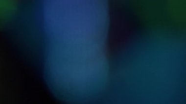 Parlak yansıma. Bulanık renkli parıltı. Odaksız mavi yeşil lens dokusu. Sanatın koyu siyah arka planında sihirli ışık titreşimi..