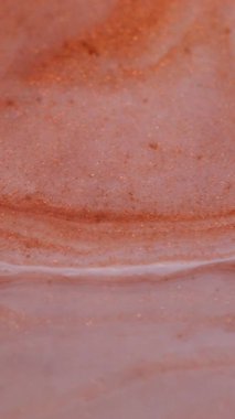 Dikey video. Pigment karışımı. Kimyasal parıltı. Turuncu bakır beyaz boya parıldayan sıvı dokuya yayılmış. Pürüzsüz karışık parçacıklar soyut arkaplanı bulanıklaştırır.