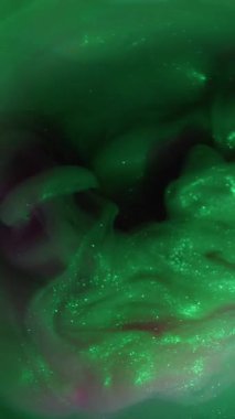 Dikey video. Işıl ışıl. Duman karışımı. Yeşil mor renkli pigment karışımı sisli siyah su arka plan dairesi ışık odaklı lens soyutlaması .