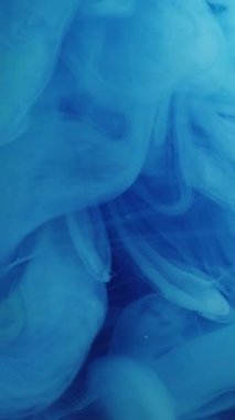 Dikey video. Duman bulutu. Mavi sis. Havadan renkli sihirli dalgalı girdaplar döküldü. Suyun soyut arka planında yumuşak kabarık dalgalı boyalı fantezi dokusu.