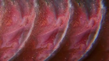 Parıltılı bir karışım. Bulanık mürekkep akışı. Yuvarlak merceğe dökülen parlak renkli şelale. Siyah sıvı bulanık arkaplanda çözünen kırmızı boya.