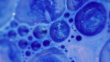 Mürekkep lekesi. Odaklanmamış ıslak damla. Yanıp sönen köpüklü boya parlak mavi renk yağ sıvısı soyut modern arka planda hareket ediyor..