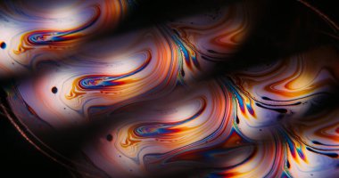 Parlak boya bulanıklığı. Yanardağ yağı. Siyah arka planda renkli benzin yuvarlak ışık lensi. Yakıt eğrisi sıvı soyut dokuyu harmanlıyor.