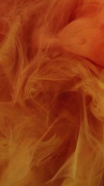 Dikey video. Sanat dumanı. Renkli sis. Yanardöner kıvrımlar parlak, yanardöner su soyut arka planında akar. Odaklanamayan turuncu boya akışı..