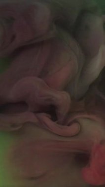 Dikey video. Boya patlamış. Sis dokusu. Odaklanmamış kırmızı sisli mürekkep buharı sıvı duman bulutu soyut yeşil sanat arka planında parıldıyor.