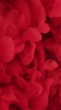 Dikey video. Dalgalı duman. Kırmızı sis. Parlak mürekkeple sıvıyı karıştırıyorum. Parlak su soyut arka planında şeffaf pürüzsüz bukleleri olan tuhaf akış boyası..