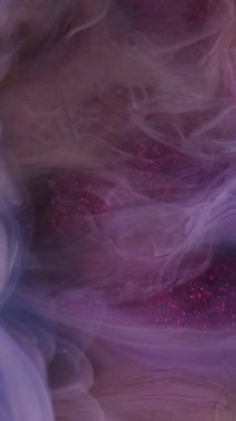 Dikey video. Mürekkep karıştırıyorum. Dumanı karıştır. Odaklanmamış mor renkli bulanık boya bulutu soyut ışıldayan sanat arka planında ışıldıyor..