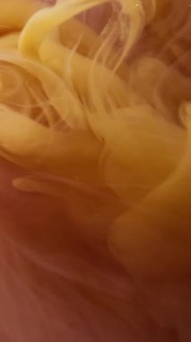 Dikey video. Fantezi dumanı. Boya dumanı. Kahverengi suda suluboya sarı sprey boya. Akış odaklı bulanık dokusu olan çevresel mürekkep arkaplanı.