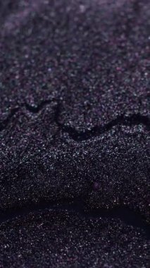 Dikey video. Parlayan koyu sıvı. Sihirli damla. Fantezi sıvı akışı parlayan volkanik siyah gri gri gri kumlu mürekkep dalgası soyut odaklanmış arka plan.