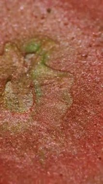 Dikey video. Parıltı patlaması. Işıl ışıl dökülüyor. Turuncu bakır mürekkep sıvısı merkezi leke sıvı karışım parçacıkları yeşil soyut bulanık arkaplan dalgası.