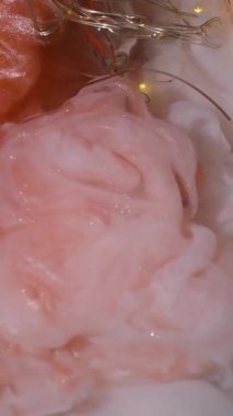 Dikey video. Duman patladı. Boya karışımı. Parlak turuncu mat beyaz sanat sıvısı akıntıları. Kırık ampulün üzerinde çakışan dumanlı mürekkep spreyi..