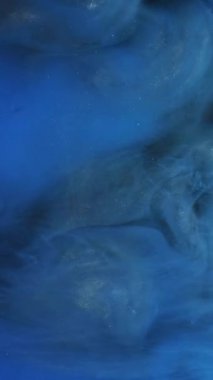 Dikey video. Parlak sis. Parlak duman. Odaklanmamış mavi renkli bulut dumanı parıltılı boya mürekkep desenini soyut altın sanat yapısına, açık arkaplan desenli.