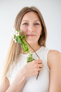 Doğal güzellik. Huzur içinde. Çekici yüz, rahatlamış kadın. Çiçek açan yasemin çiçeğinin tadını çıkarıyor. Sanatın beyaz arka planında yeşil dal..