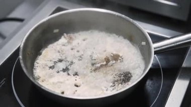 Yahni sosu. Baharatlı sıcak yemek. Şefin eli kaynamış beyaz sıvıda eti tavaya koymak için karabiber tuzu ekliyor. Ocakta kaynayan buharlı yemekler..