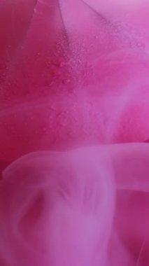 Dikey video. Sis dalgası. Suluboya mürekkep. Renkli suya dökülen zarif pembe peçe. Soyut arka planda çözünmüş elmas..