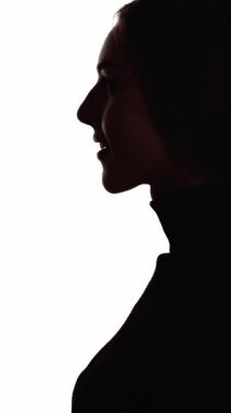 Dikey video. Dua silueti. Affetme inancı. Minnettar olan mutlu kadının yüzü beyaz kopya arkaplanında izole edilmiş koyu renk karşıtlık profili ana hatları.