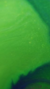 Dikey video. Boya karışımı. Islak doku. Odaklanmamış yeşil renk sıvı akrilik sıvı dalgalanma parçacıkları soyut sanat arka planına sıçrar.